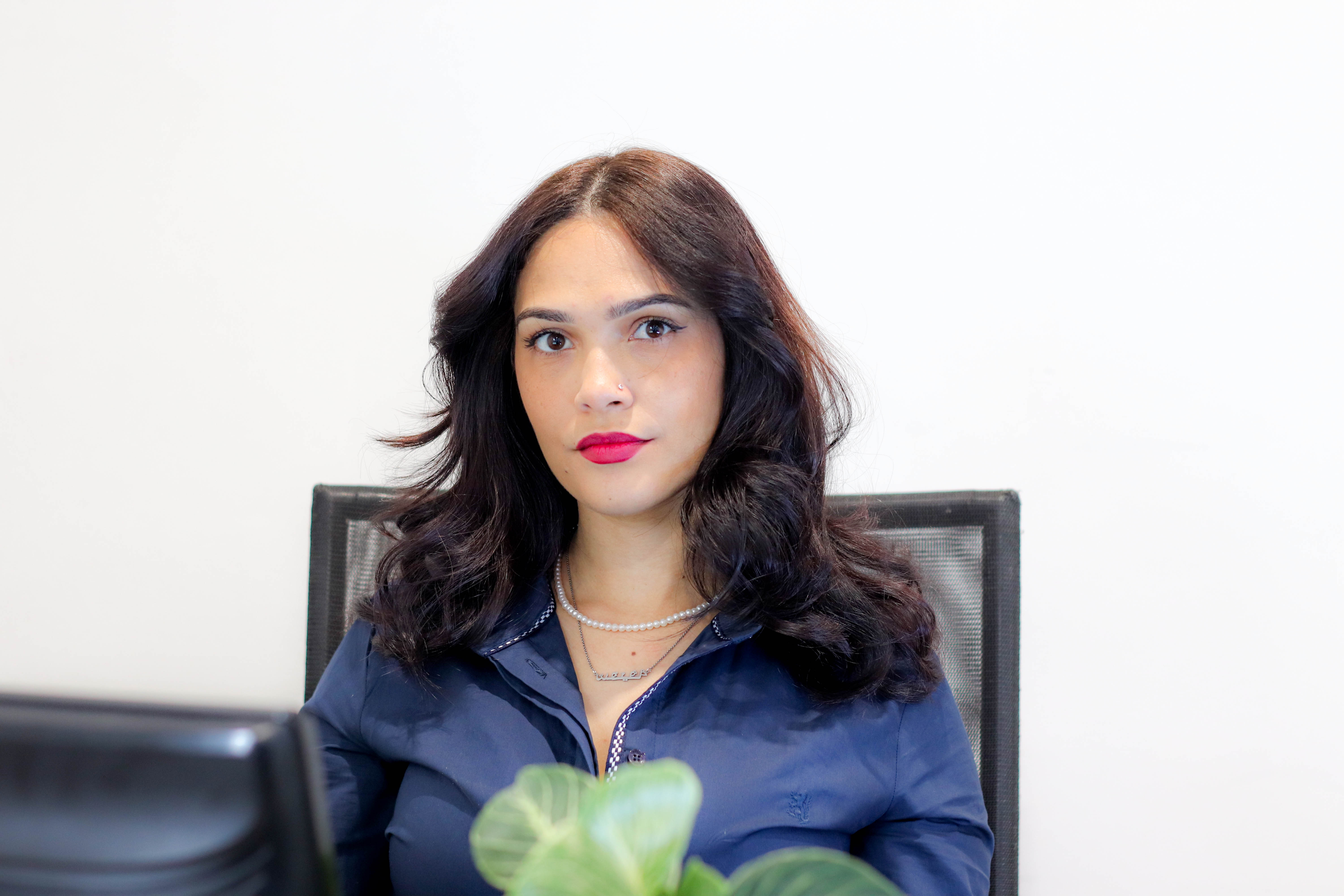 Shafiecka Jacobs sitting in an office chair with a plant in the foreground.